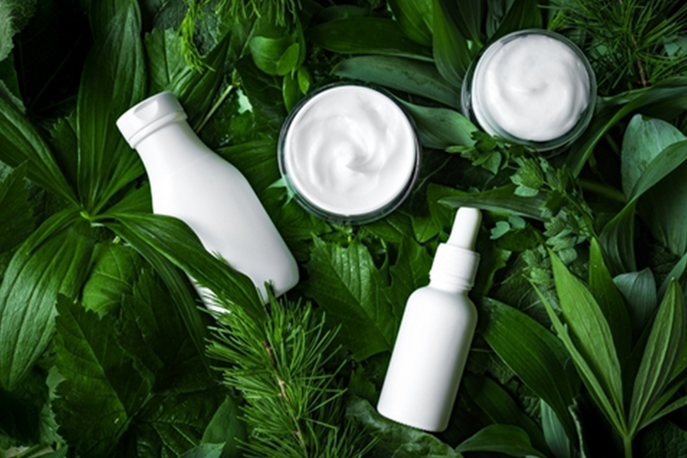 Organic cosmetic products on green leaves as background, top view. Natural eco beauty and organic vegan plant based skin care concept.